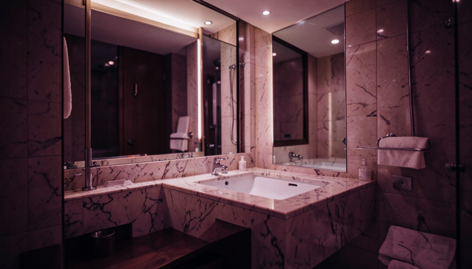 Salle de bain d'hôtel élégante avec vasque en marbre, miroir large et éclairage doux