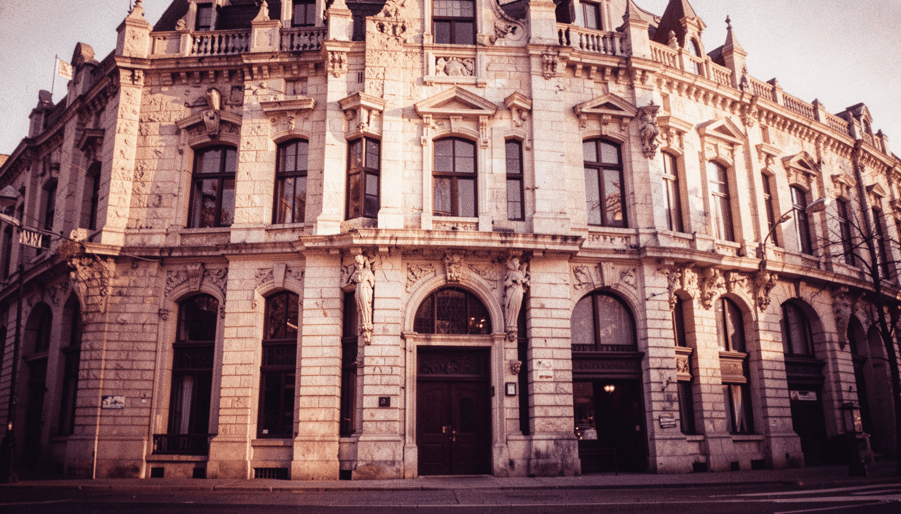 Façade historique en pierre d'un immeuble du Vieux-Montréal baignée de lumière dorée, tons chauds de beige et de gris